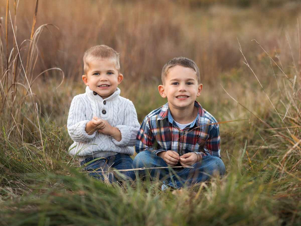 two brothers sitting in field for family photos