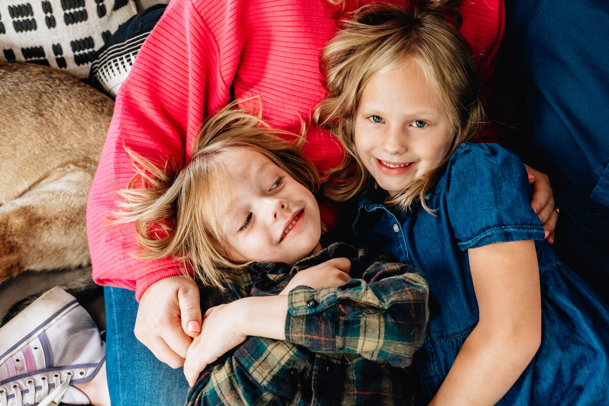 A close up of two kids laying on their mother.