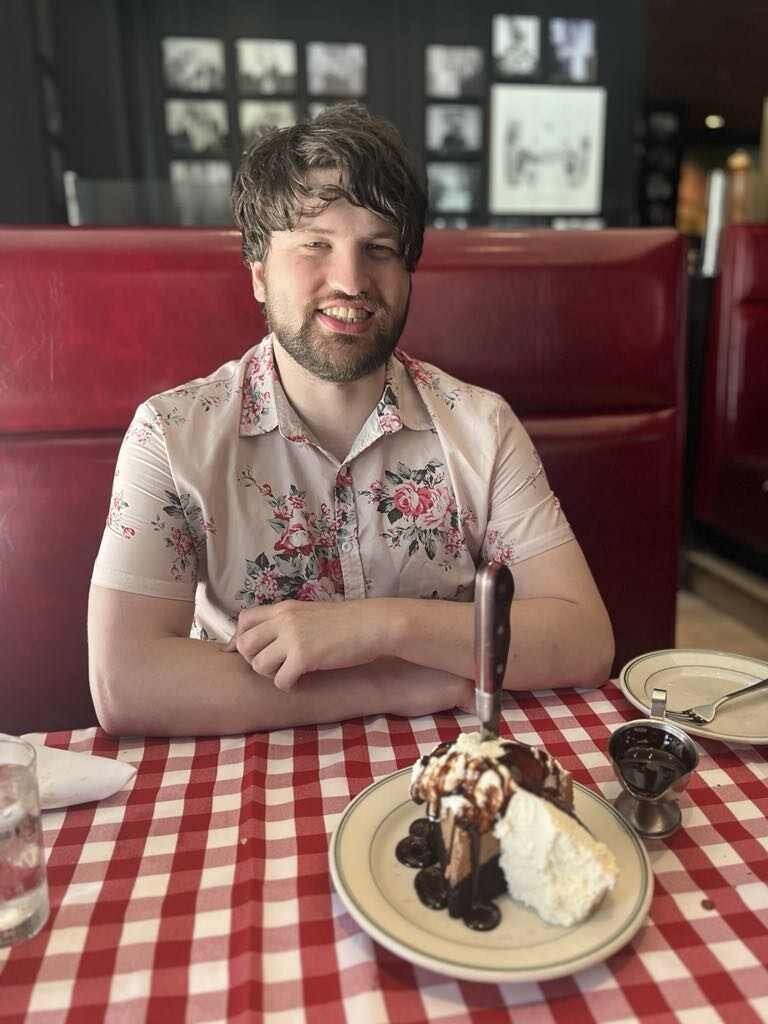 Casual, unedited dating app photo of man at a restaurant with dim lighting and no professional setup.
