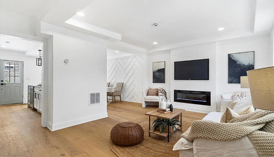 Open-concept living room remodel featuring a modern fireplace with wall-mounted TV, custom trim accents, and wide-plank hardwood floors—designed for comfort, style, and functionality.