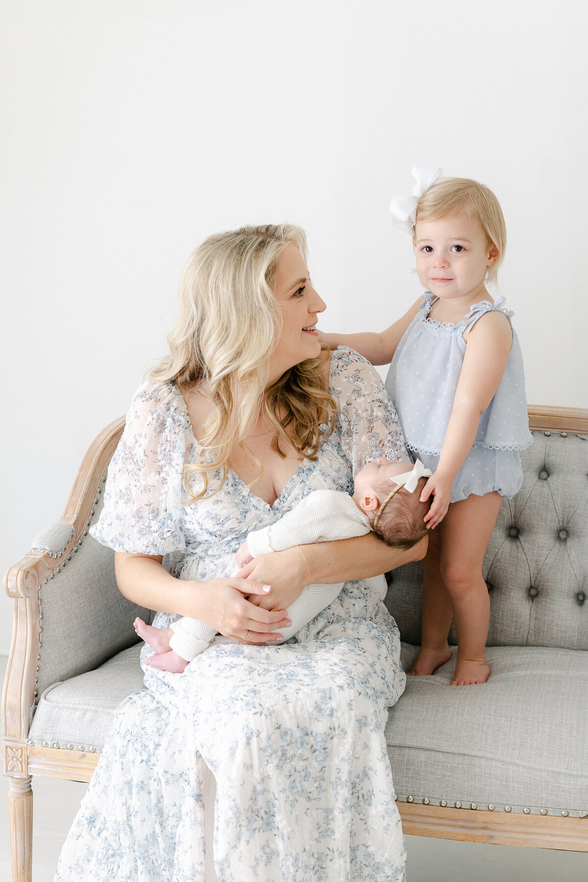 a mom looking at her toddler while holding her newborn