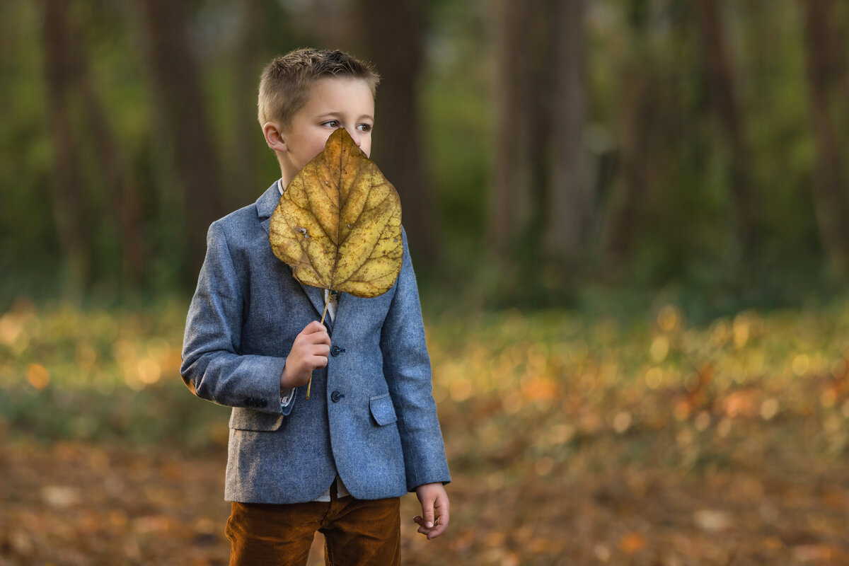 Child holds big leaf during family photography session outside in South Jersey