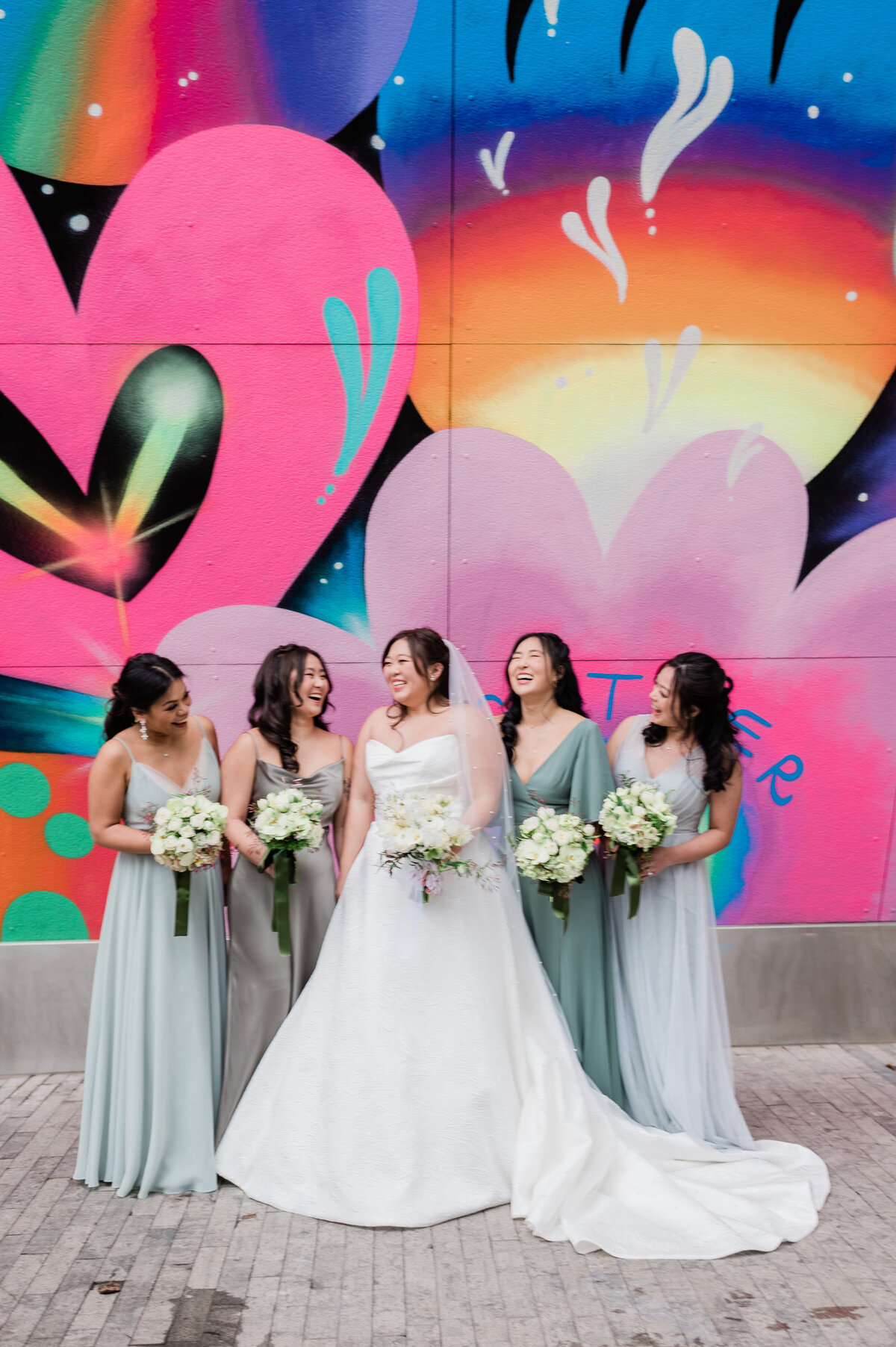 Bride and bridesmaids laughing together with bouquets in hand