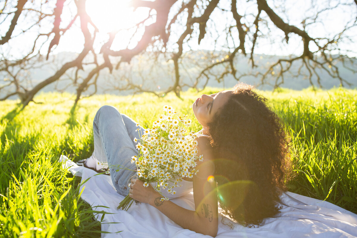 woman laying down on a blanket in a field