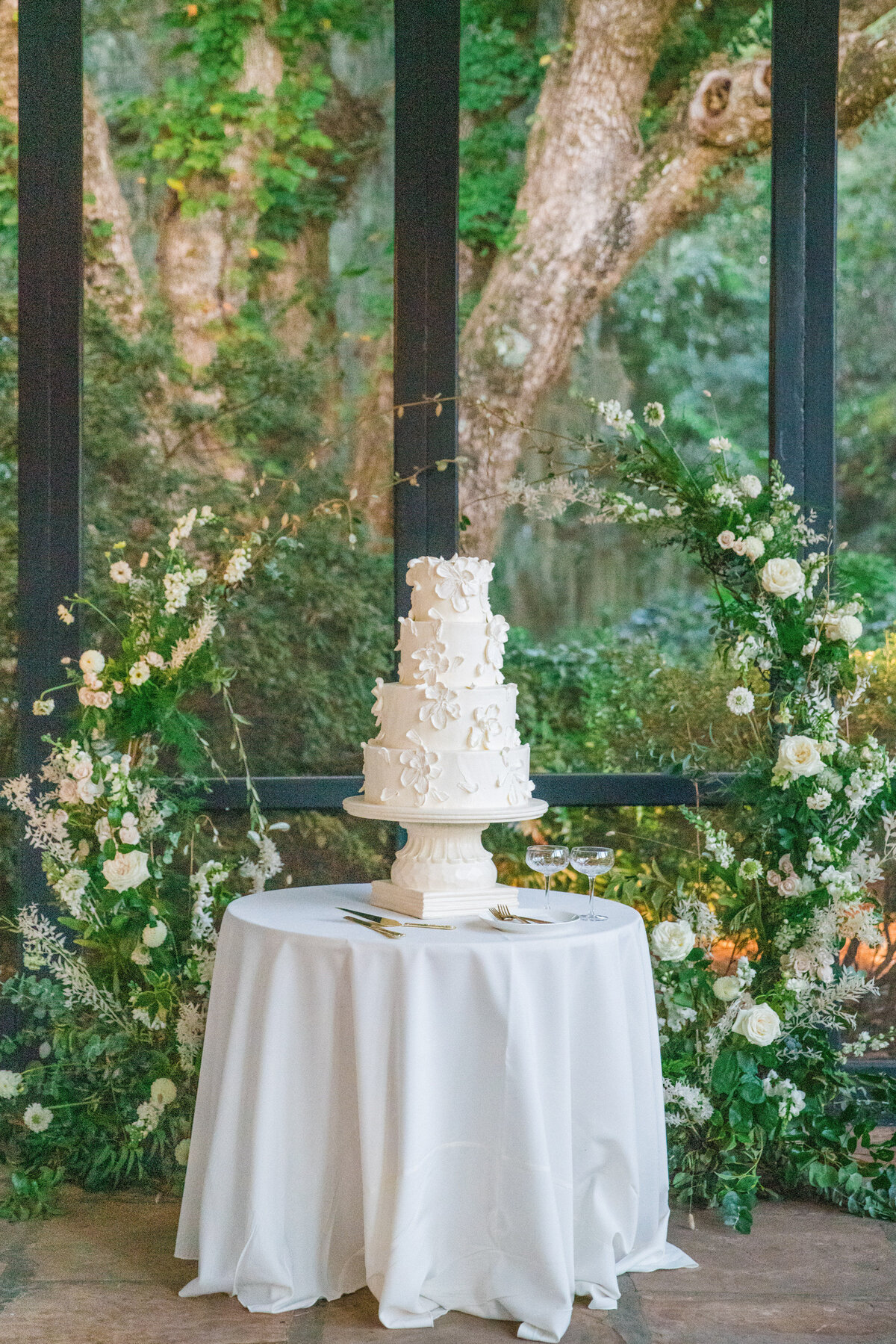 cake displayed on table with floral arch around it
