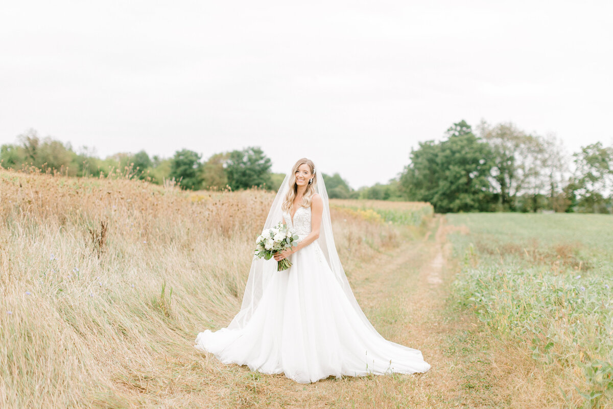 bride standing in a field smiling