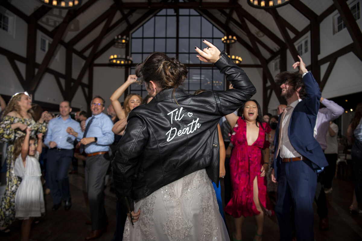 A newlywed in a leather jacket dancing at their reception 