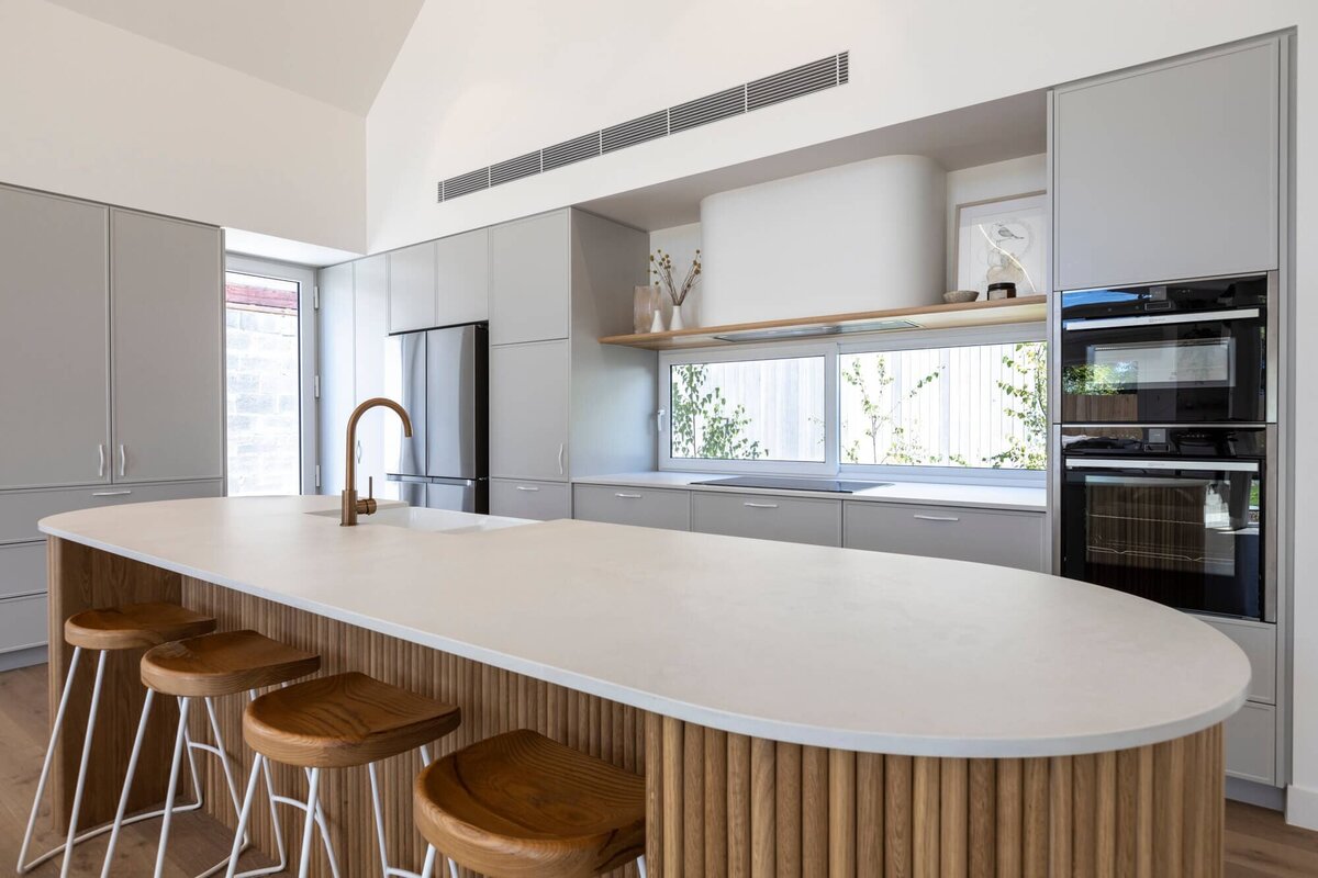 Timber cladded island with stone worktop and grey kitchen cupboards