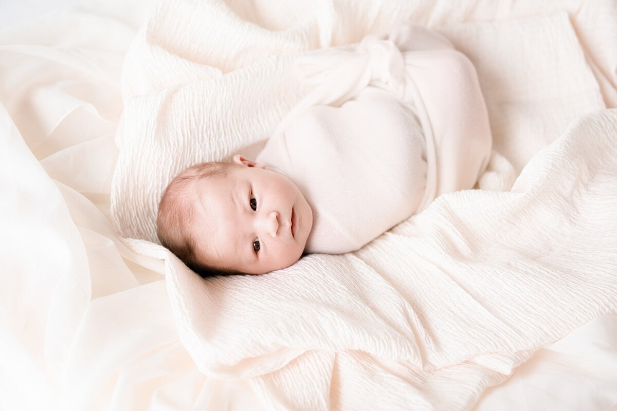 aawake baby bundled on bed