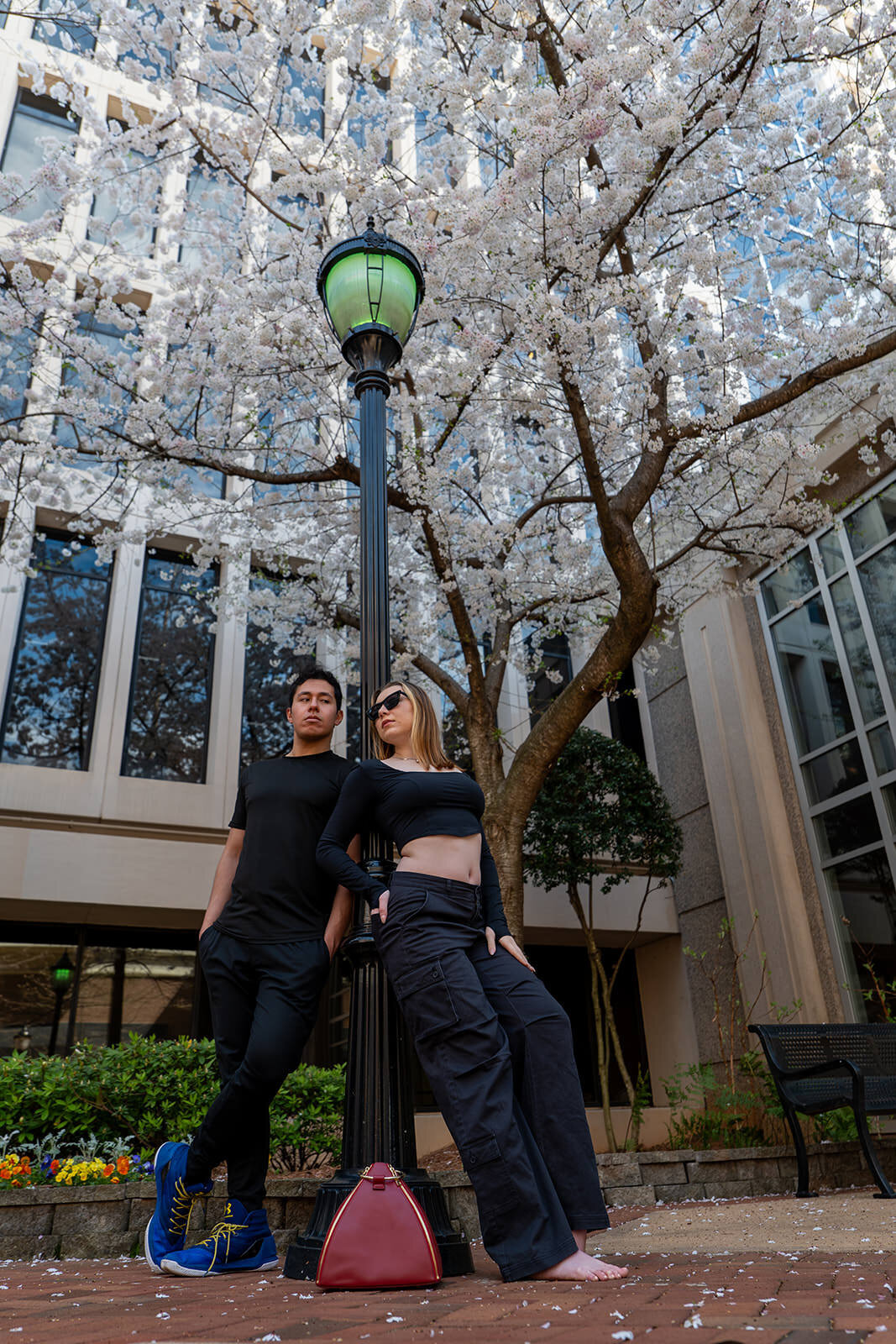 Two people standing together leaning against a light pole 