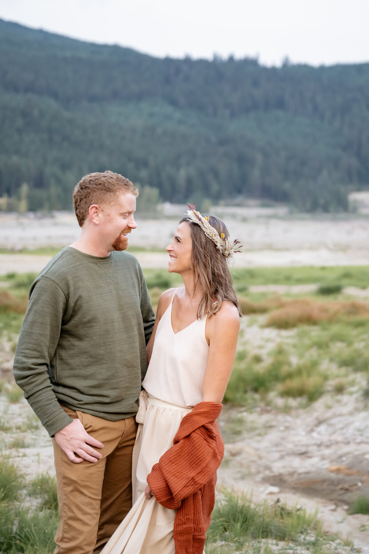 engaged couple smile at each other in snoqualmie mountains