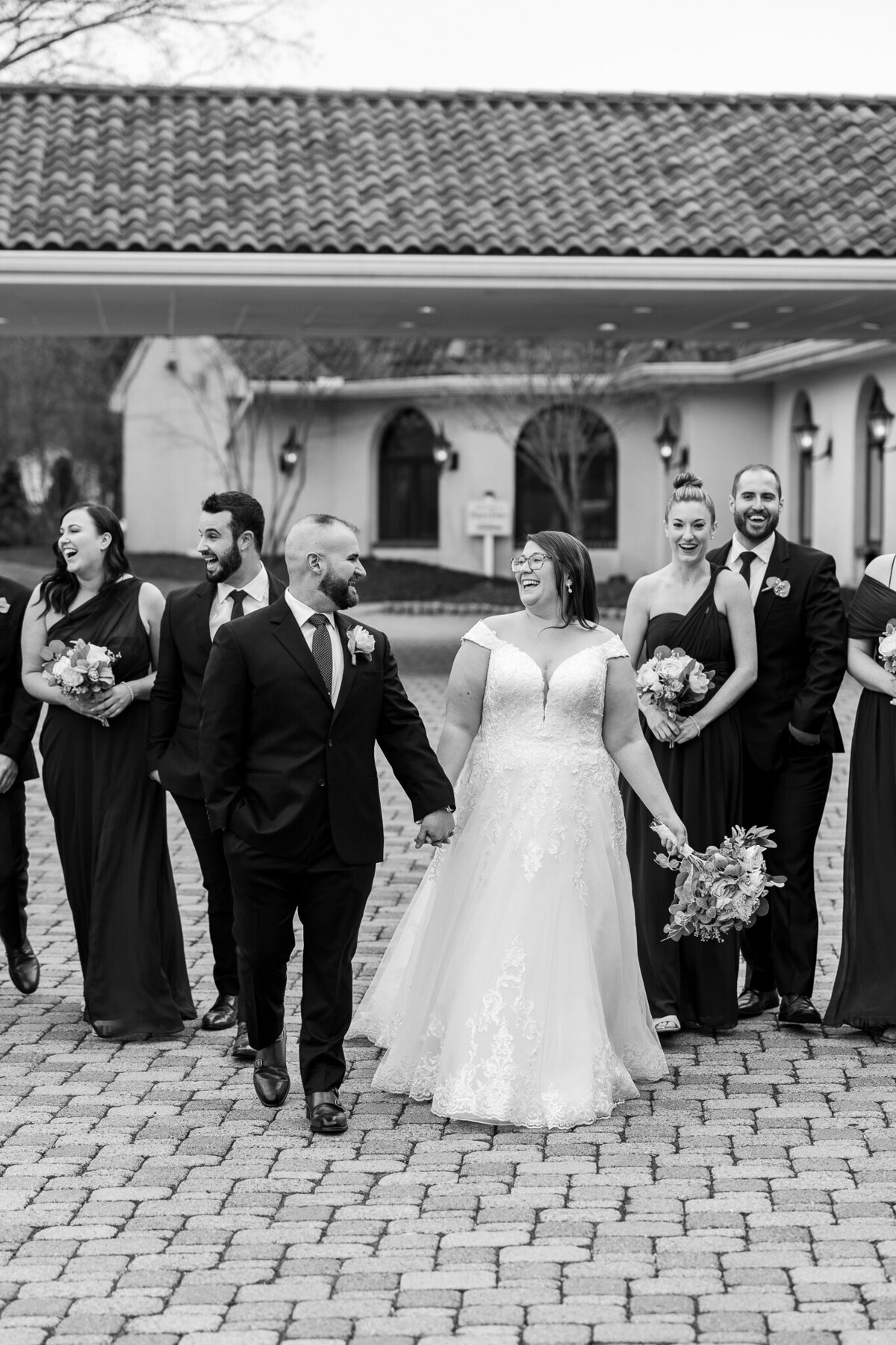Image of a bride and groom with their bridal party walking together at Perona Farms in Sparta, NJ, celebrating a fun and memorable wedding moment