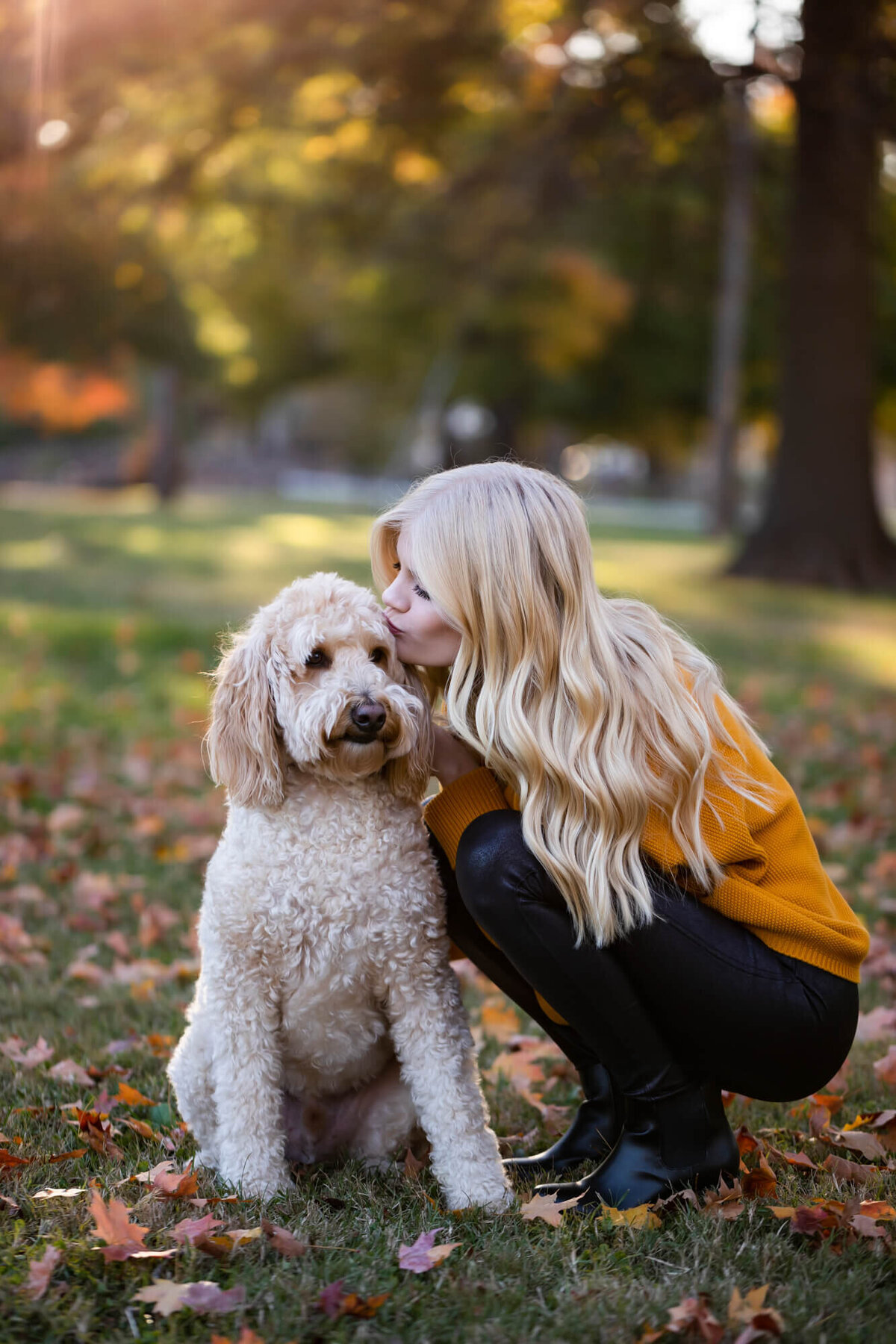A beautiful blonde teen poses with her family dog and kisses it on the cheek in her senior portrait. Captured by Springfield, MO senior photographer Dynae Levingston.