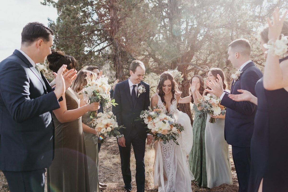 Bride and groom walk up the aisle while their wedding party cheers them on.