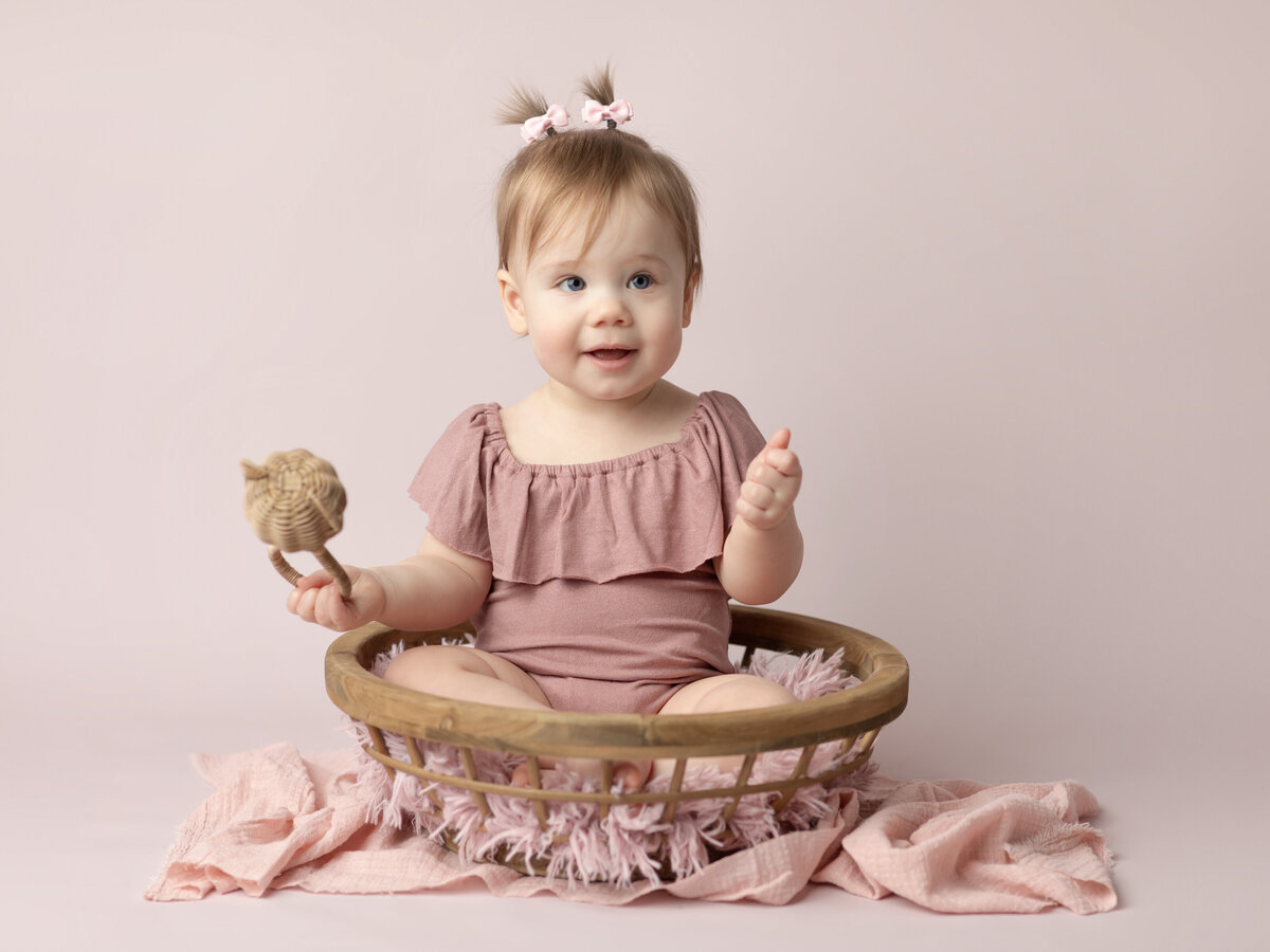 one year old girl in pink for first birthday photoshoot