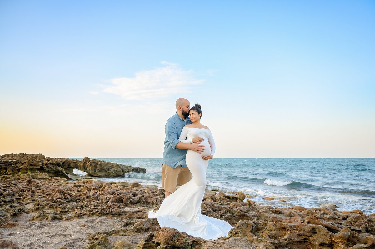 Maternity photo session on a South Florida beach near Boynton Beach, FL with soft ocean waves in the background.