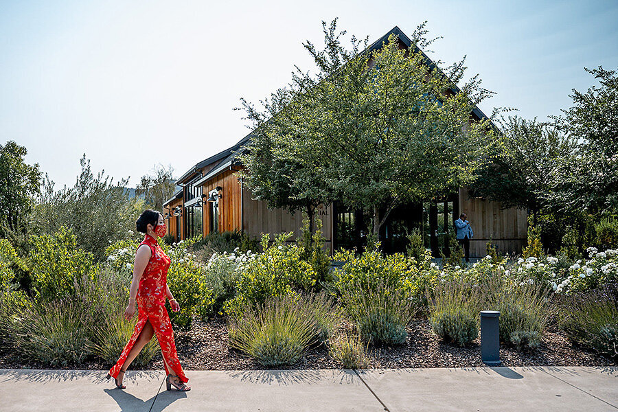 Bride in vibrant red traditional dress walking through landscaped gardens at Estate Yountville wedding venue, San Francisco Bay Area wedding photography