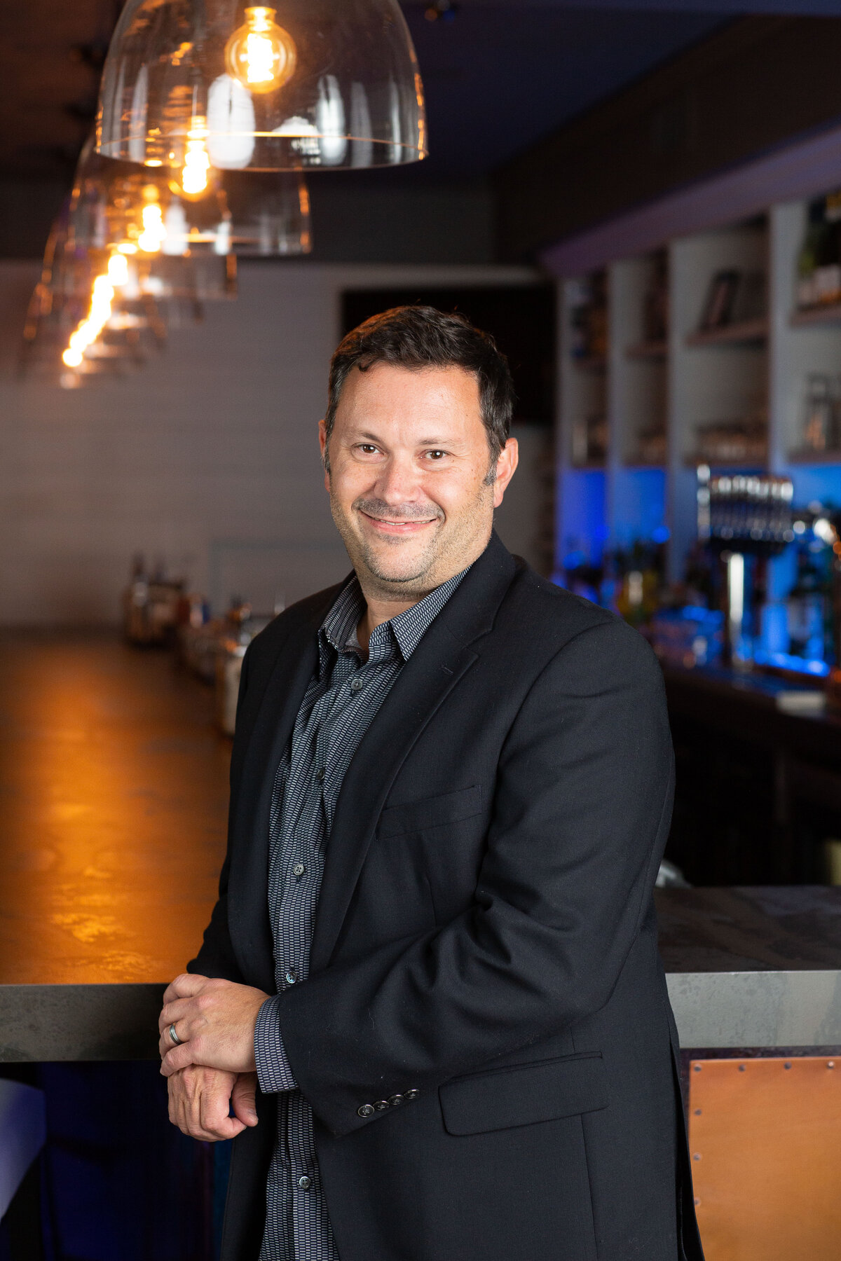 restaurant owner leaning on bar, looking at camera