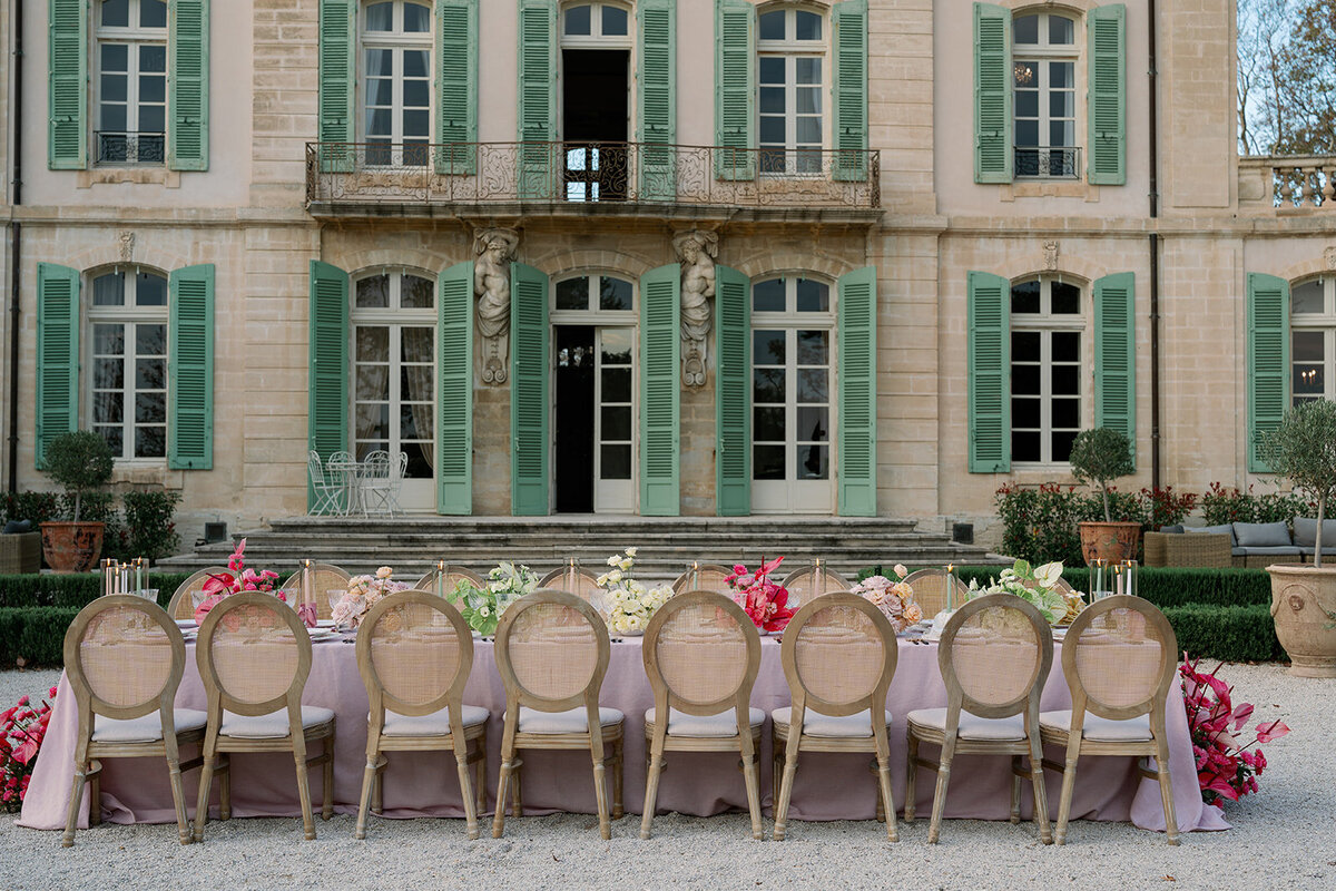 Long wedding reception table with blush linens, pink florals, and crystal glassware at Château de Tourreau.