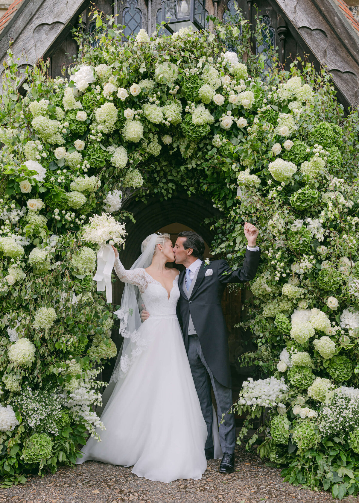 chloe-winstanley-weddings-hambleden-church-flower-arch-bride-groom-kiss