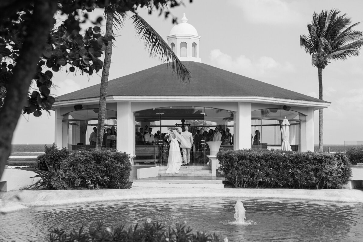 Bride and groom walk into a beachside gazebo for their Cancun ceremony, photographed by a Philadelphia photographer.