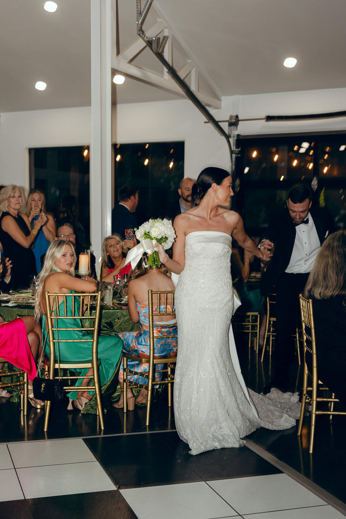 A candid wedding photo of the bride and groom entering their wedding reception