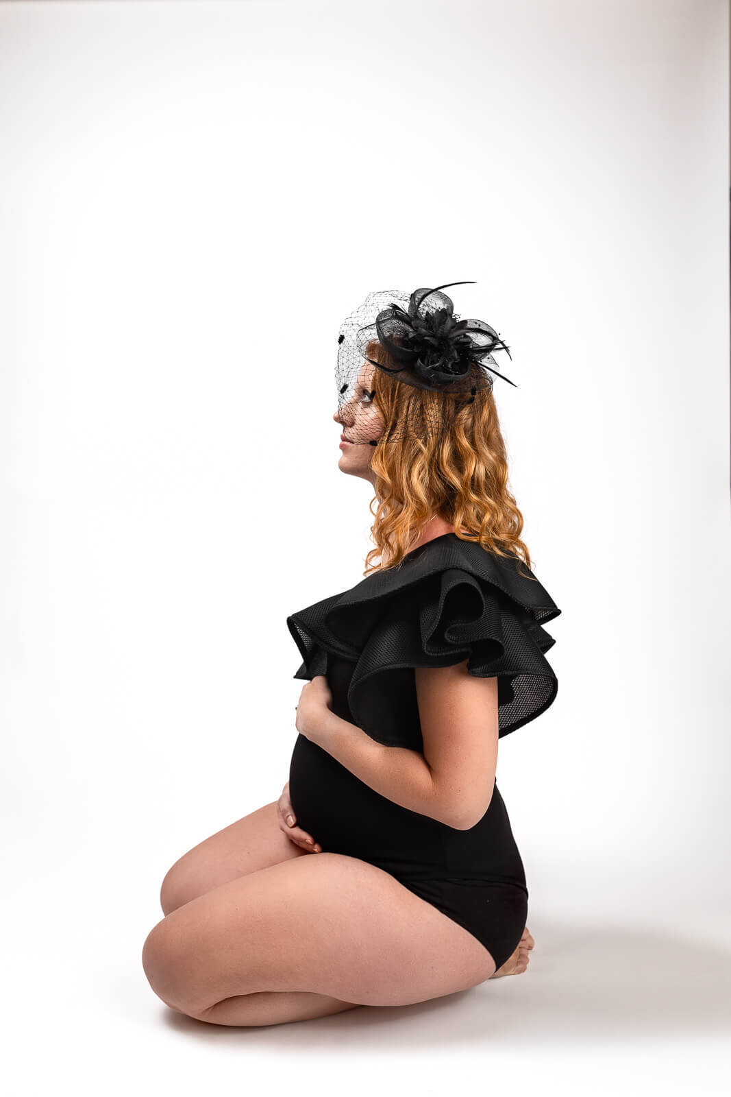 Maternity portrait of pregnant momma wearing a black body suit with birdcage hat.