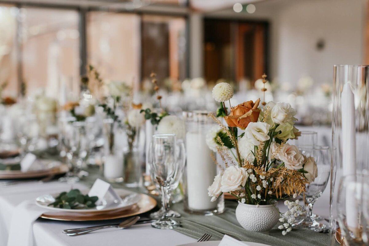 Small floral arrangements sit atop a table set for dining at a wedding reception.
