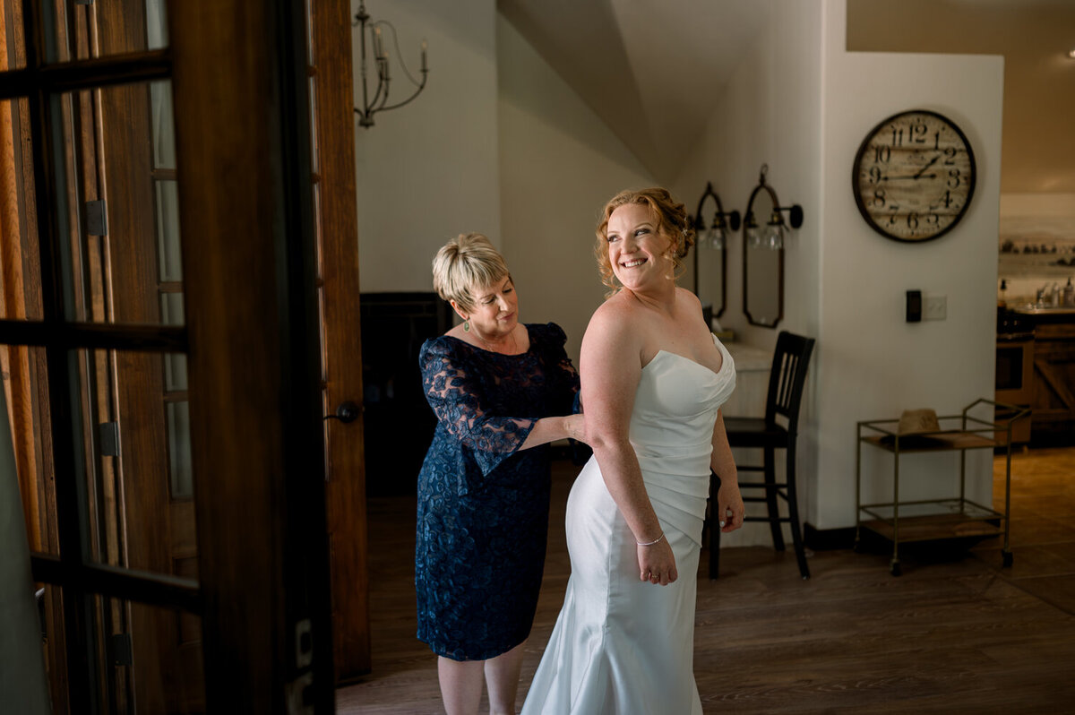 Bride's mom helping the bride with the final touches on her wedding dress during a summer wedding at The Woodlands at Cottonwood Canyon.