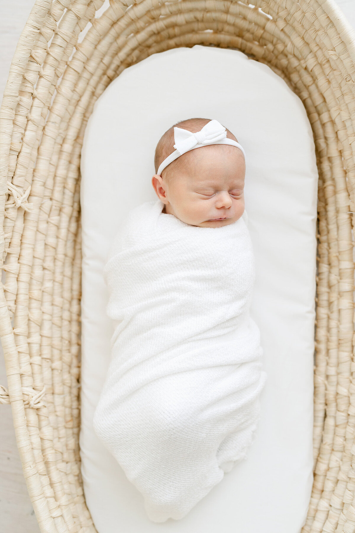 Louisville Ky newborn photographer, Julie Brock, places sleeping newborn baby in Moses basket