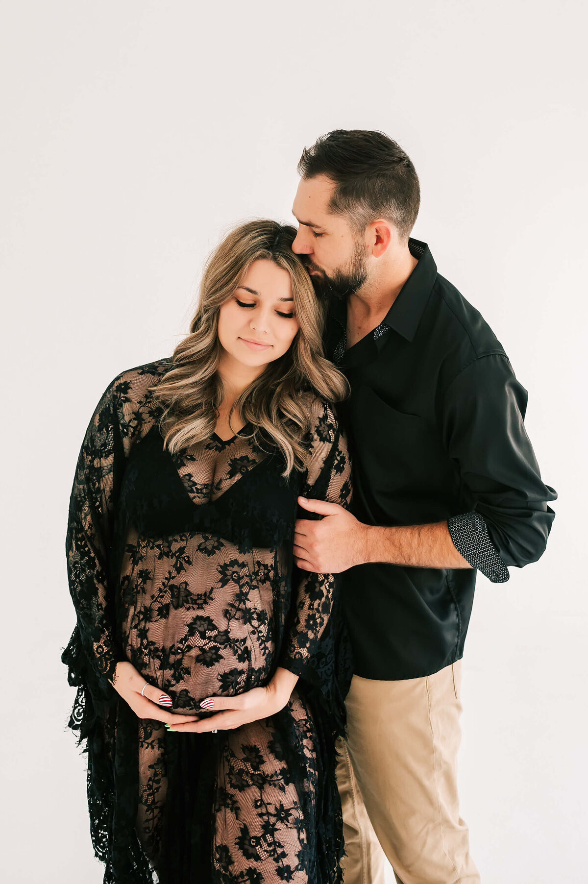 Springfield MO maternity photography of husband kissing pregnant mom in lace dress