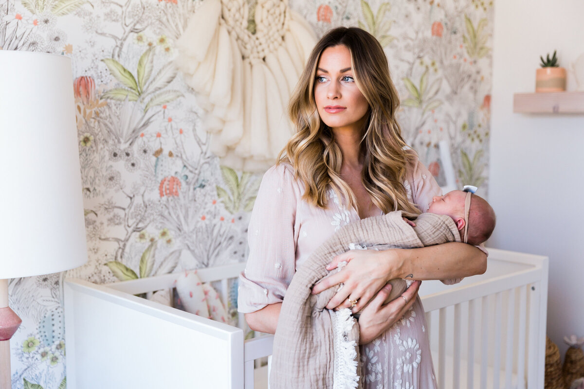 mom holding newborn baby in lifestyle newborn photo session