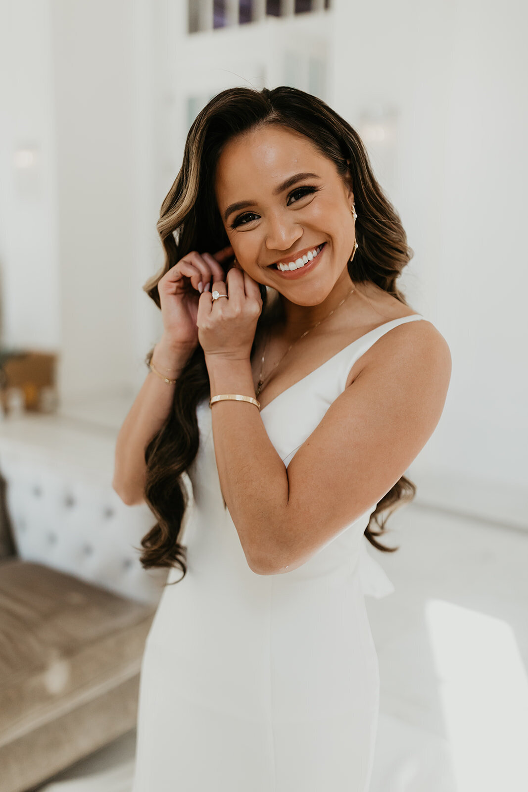 Asian Bride putting on earrings smiling at camera