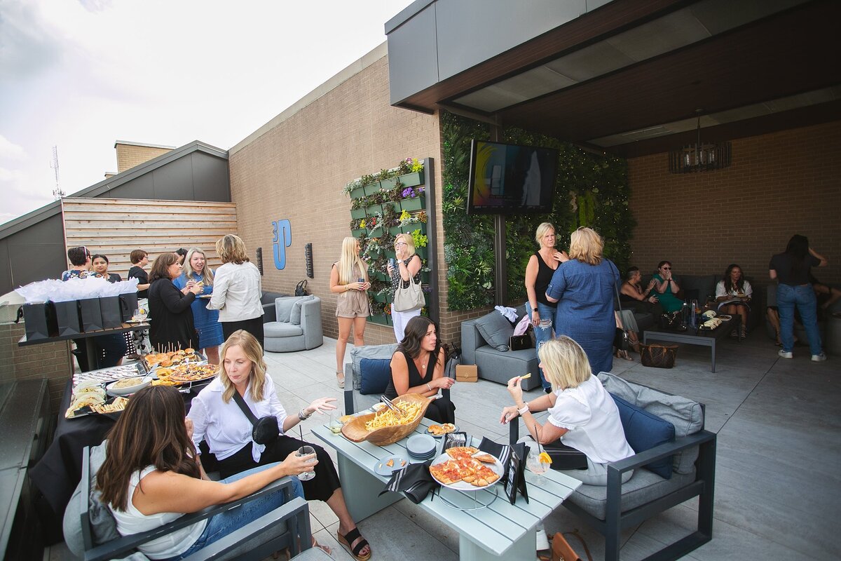 a-group-of-professionals-enjoying-an-outdoor-rooftop-networking-event-in-carmel-indiana-with-food-drinks-and-conversation
