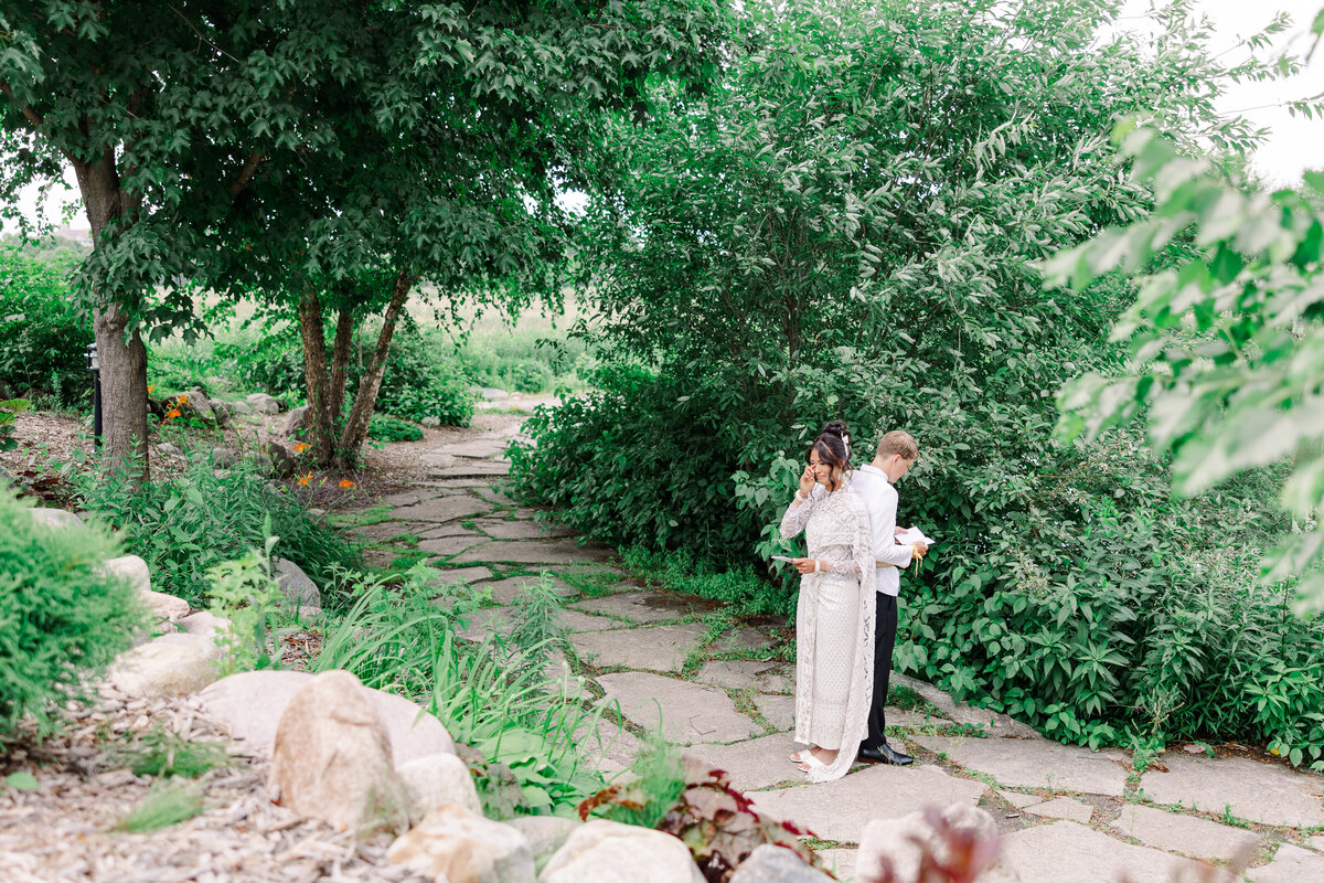 bride and groom reading letters on path  taken by mpls wedding photographers