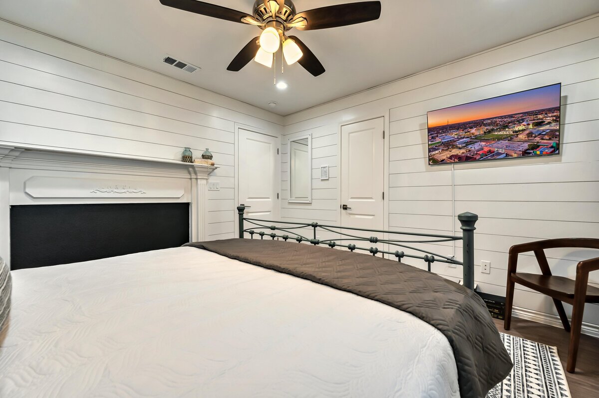 Bedroom with comfortable bedding and smart TV in this four-bedroom, 4.5 bathroom new construction vacation rental house with free wifi, fire pit, gazebo, cornhole, private bathrooms for each bedroom within walking distance of Magnolia and Baylor in downtown Waco, TX.
