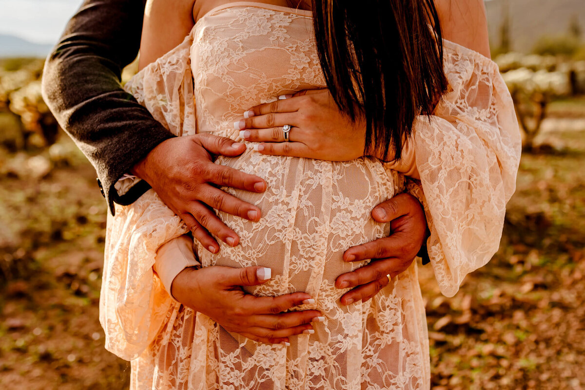 parents holding maternity bump during photography session in Arizona