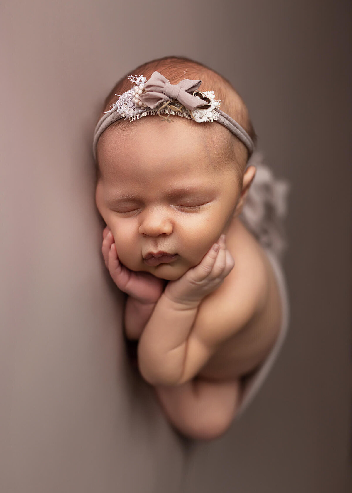 Baby girl wrapped in a lilac wrap with a matching floral headband, Southern Minnesota newborn photographer.