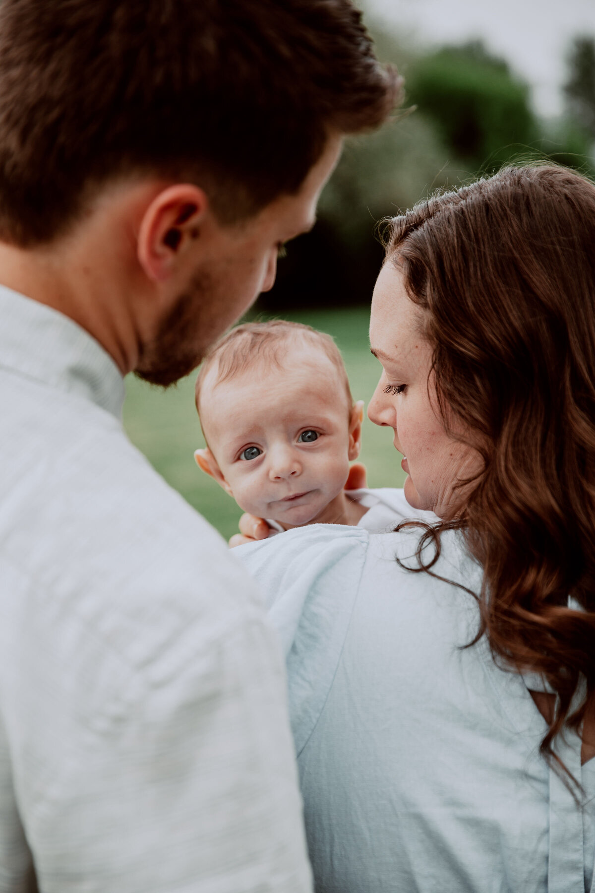 Idaho Falls newborn photographer photographs mother holding newborn baby boy as the father stands close