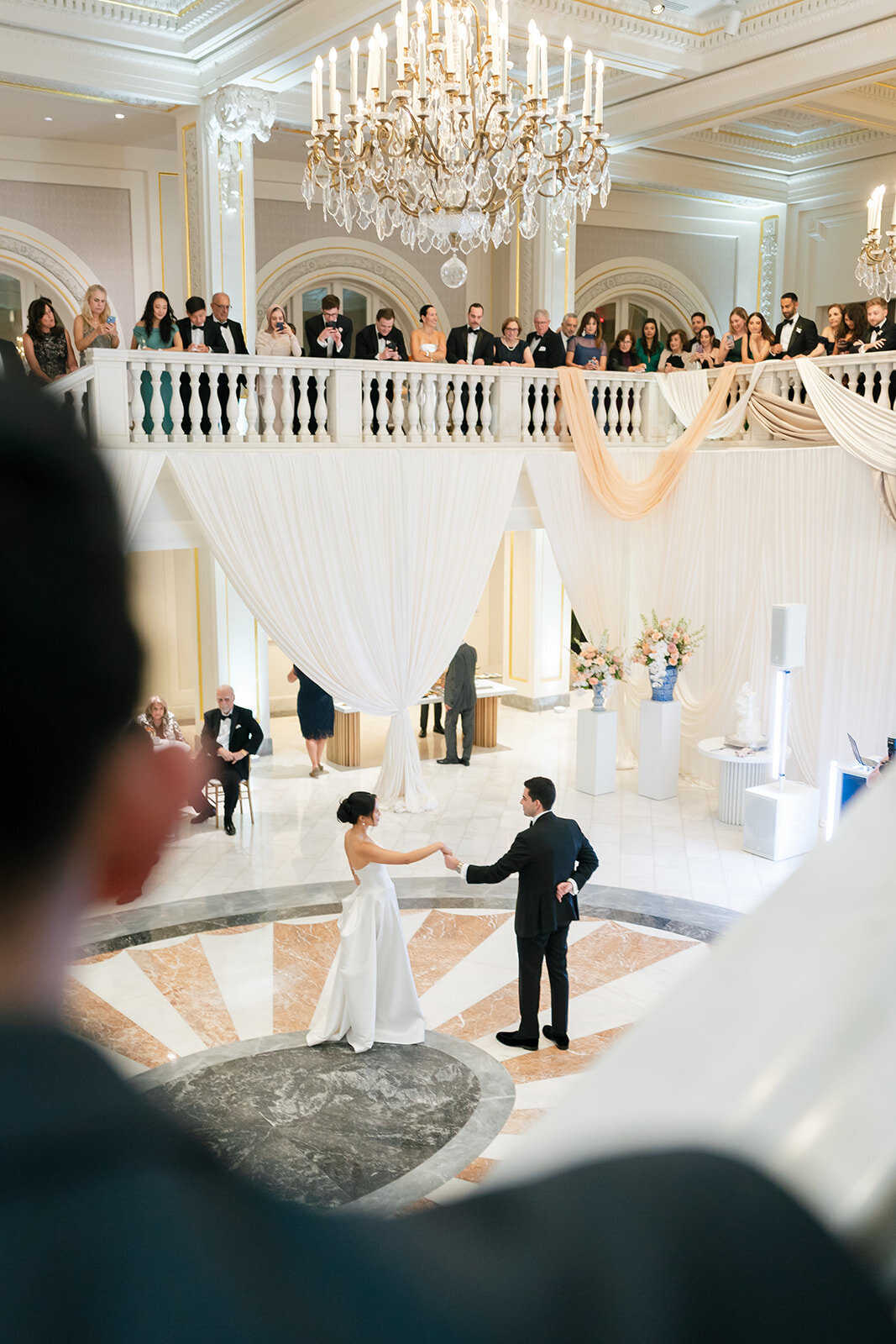 Bride and groom dancing with guests watching from above at the National Museum of Women int he Arts. 