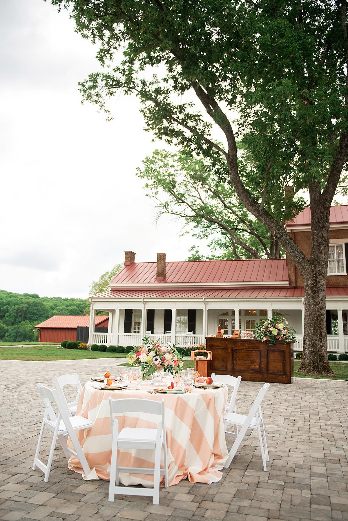 garden party with striped table cloth and large flora centerpiece at Ravenswood Mansion