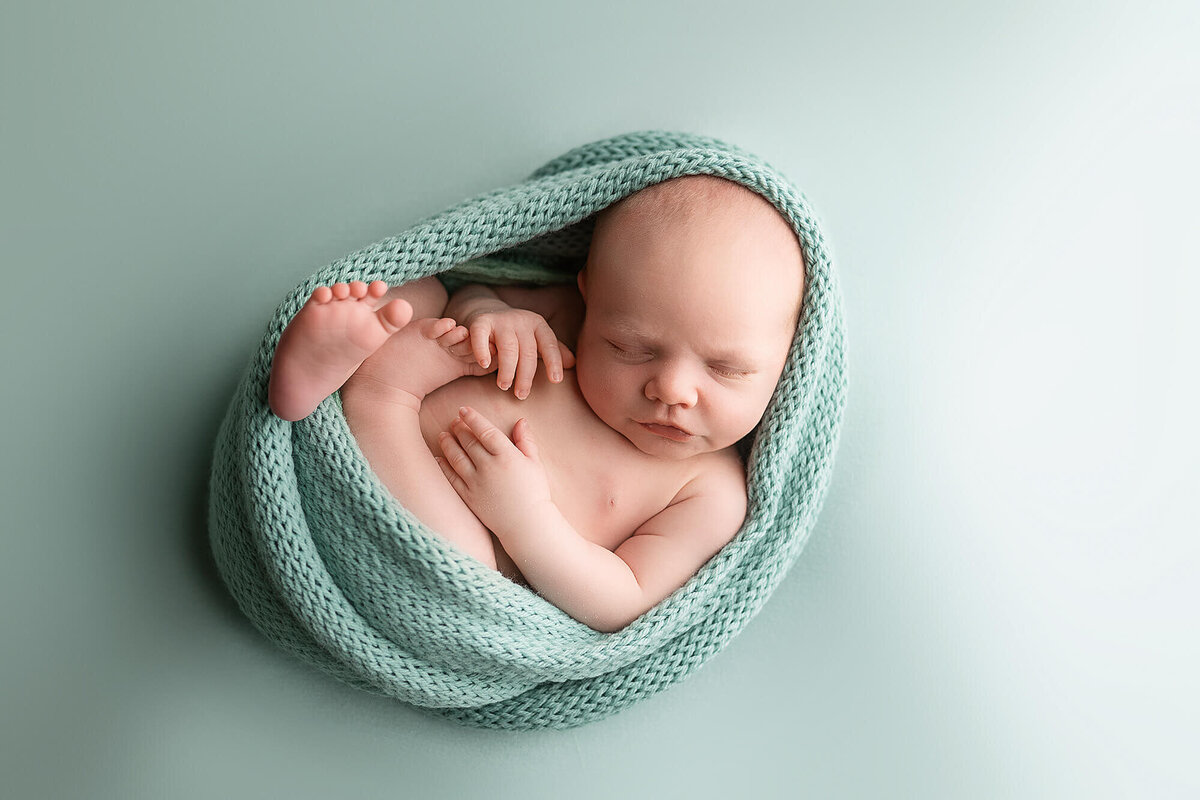 Baby boy wrapped up in a hand knit blanket.