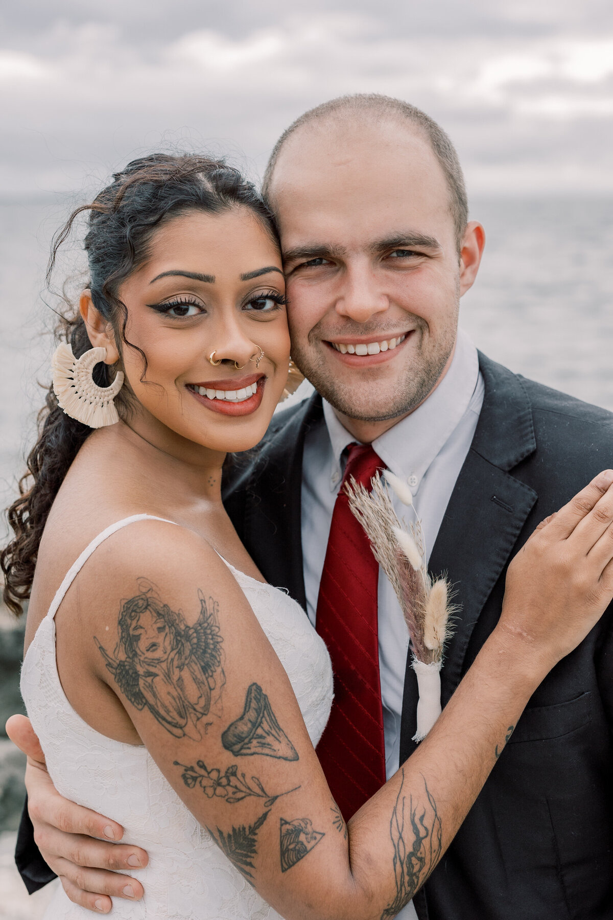 Interracial couple smiling cheek to cheek on their wedding day at a beach in Florida.