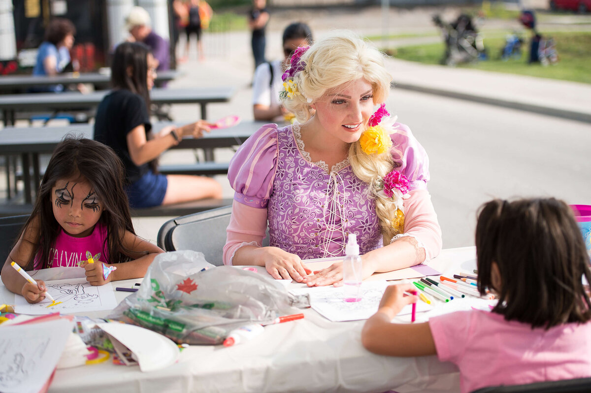 Ottawa event photos showing a woman dressed as a princess interacting with children as they do crafts during a corporate children's event.  Captured by JEMMAN Photography COMMERCIAL