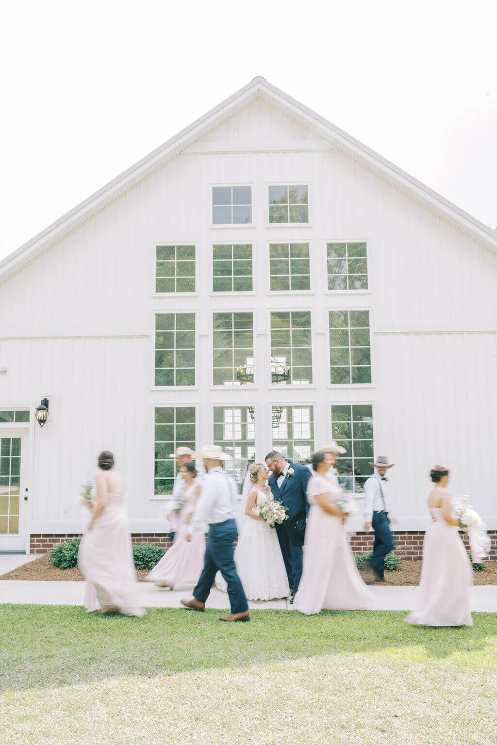 Couple kissing while wedding party walks around them blurred