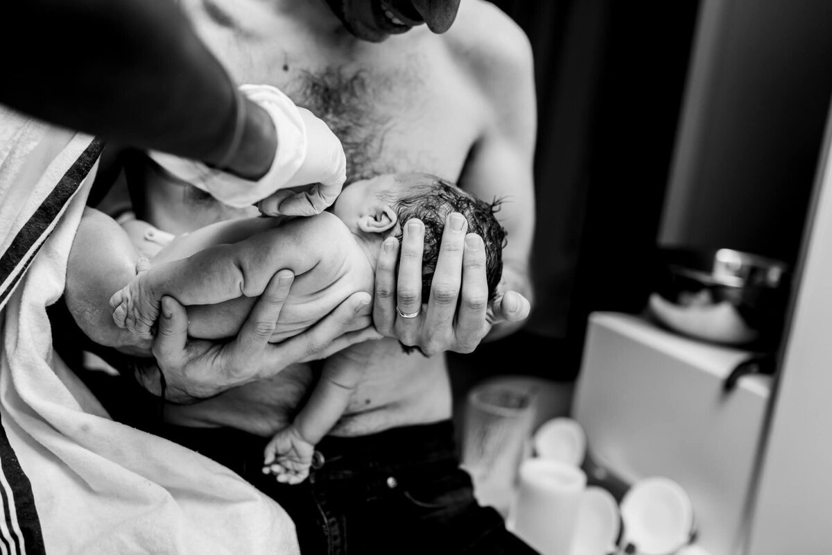 Father embracing newborn baby after waterbirth at Toronto Birthing Centre.