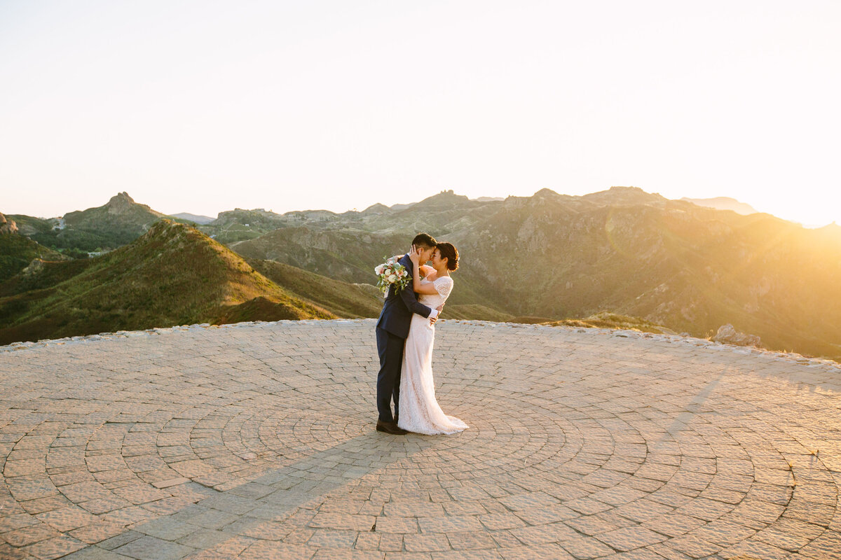 bride and groom embrace on a helicopter pad during sunset