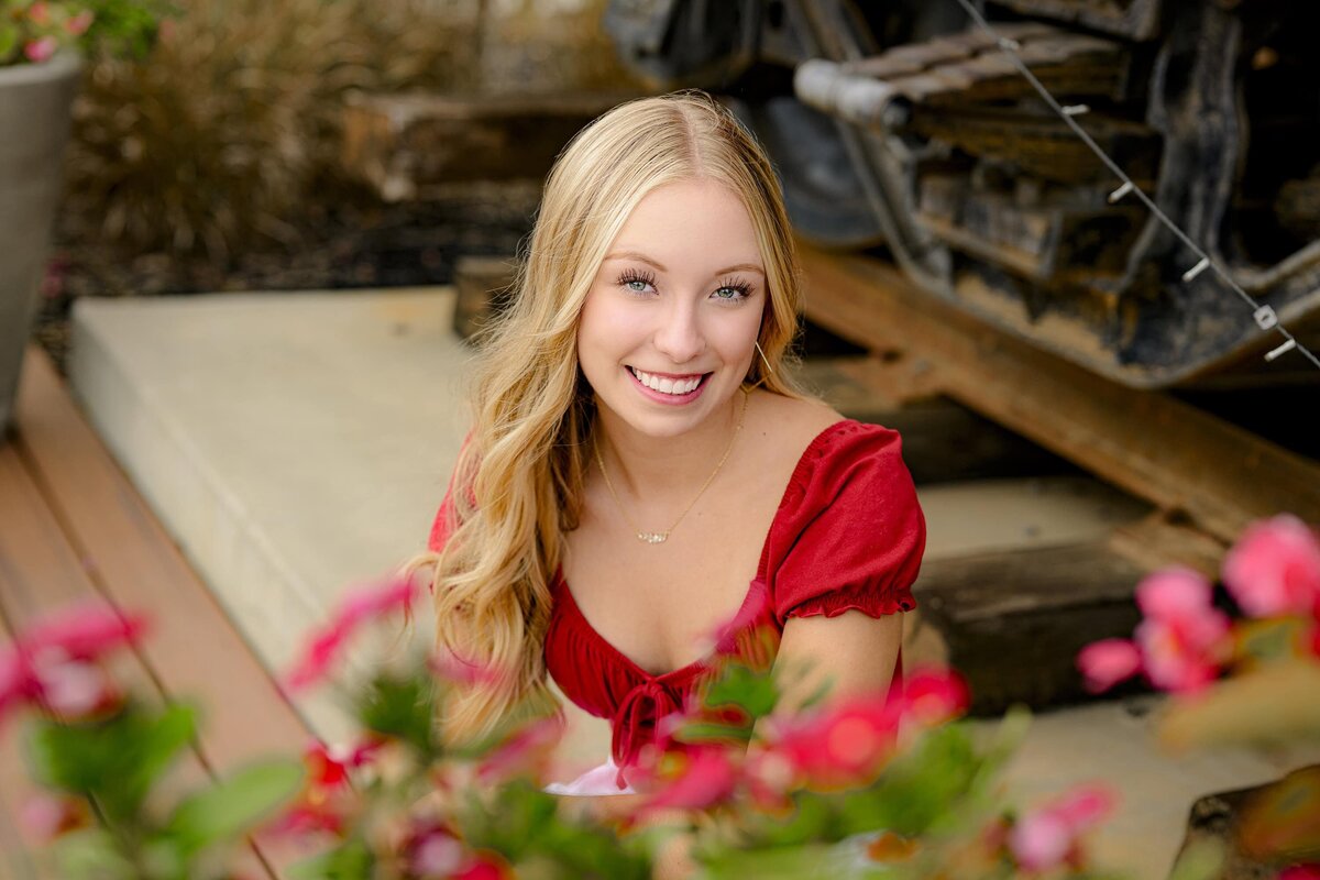 blonde charlotte senior poses in a red top with flowers in the foreground  in Rock Hill, SC