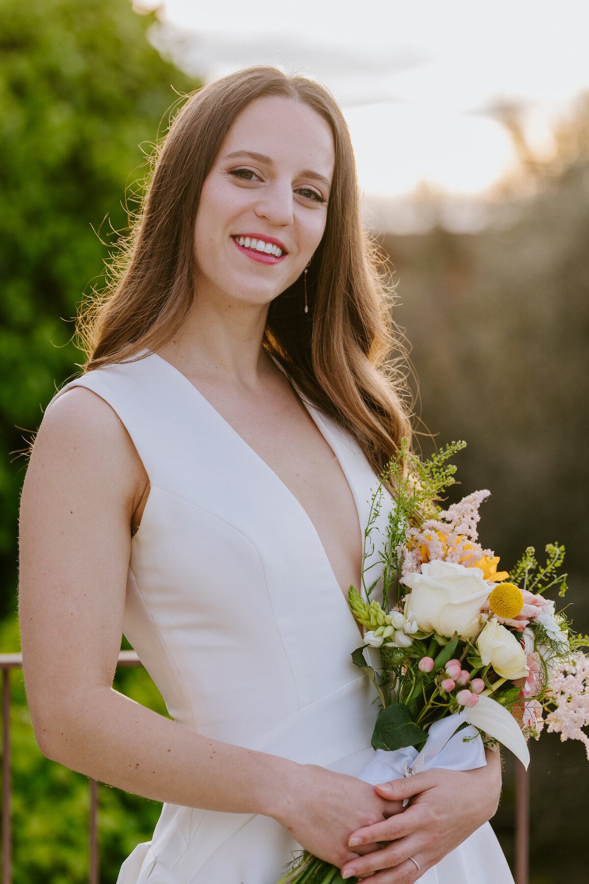 Bride holding pastel bouquet with yellow and peach flowers