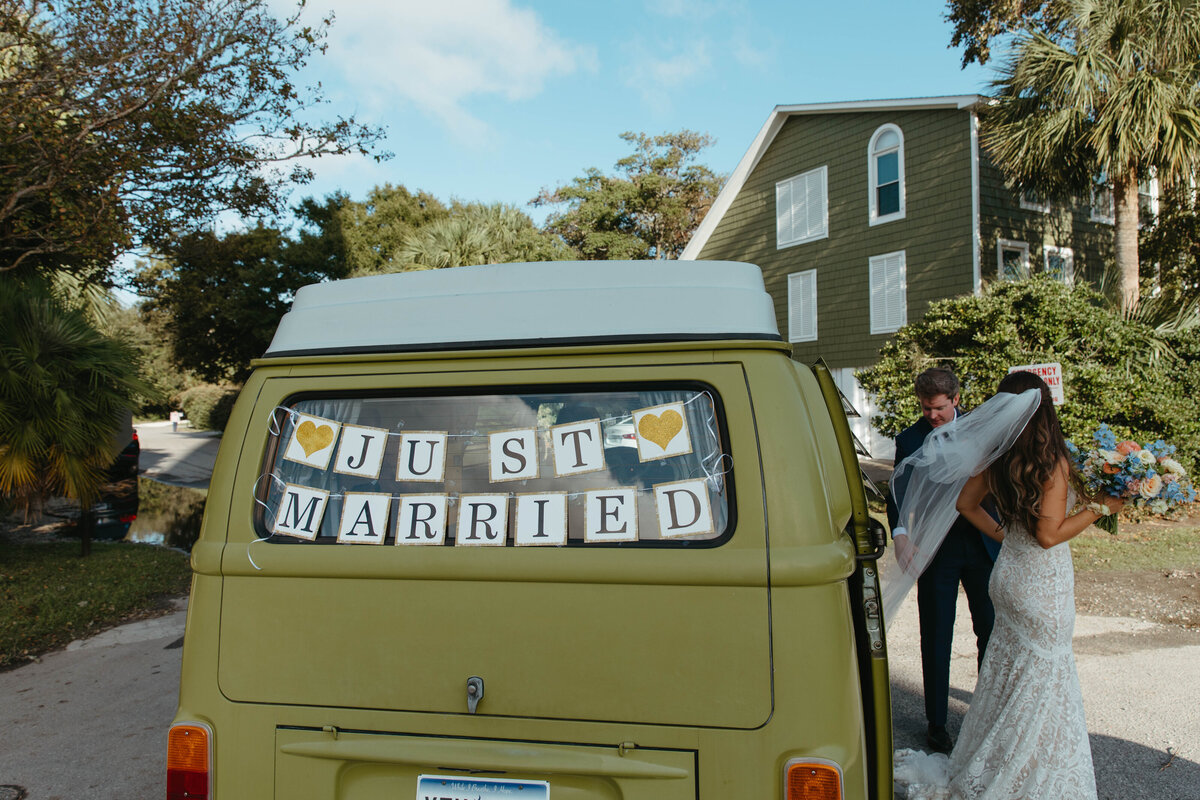 Bride and Groom walking out of green VW bus with "Just Married" sign